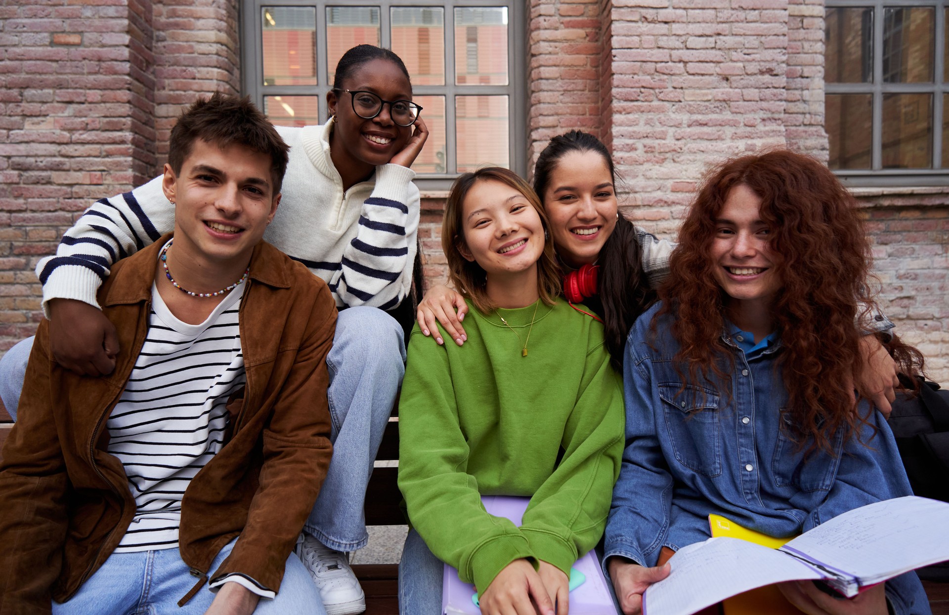 Portrait of a group of student friends gathering at university campus looking at camera smiling.